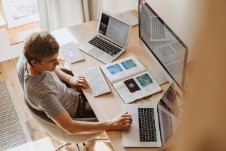 a man working remotely using his 3 computers